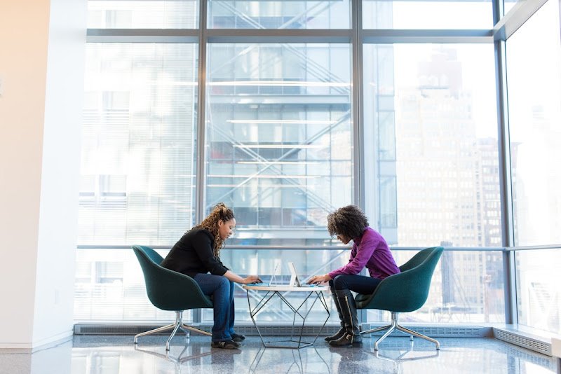 Two professionals in an office sitting around the table discussing the strategic value of knowledge management in organizational growth